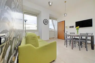 a living room with a green chair and a table at Homely Flat Porta Maggiore in Rome
