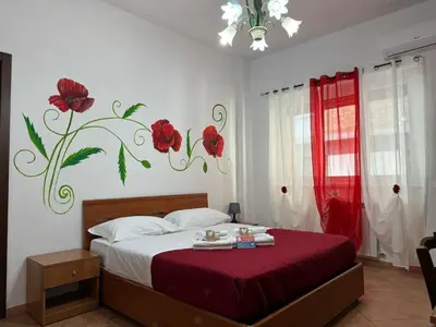 a bedroom with a bed with red flowers on the wall at Trastevere Marconi Apartment in Rome