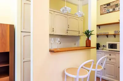 a kitchen with white cabinets and two white chairs at Casa Rio by Hili in Rome