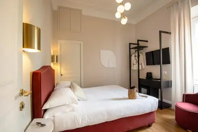a bedroom with a white bed and a red chair at Daplace - Santa Susanna Suites in Rome