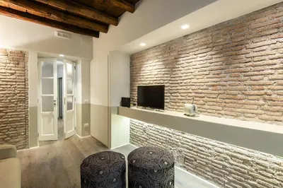 a living room with a brick wall and two stools at Luxury Fori Imperiali Apartment in Rome