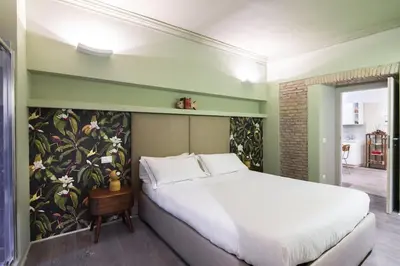 a bedroom with a white bed and a floral wall at Luxury Fori Imperiali Apartment in Rome