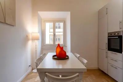 a white kitchen with a table with a vase on it at Toscana 6 - FromhometoRome in Rome