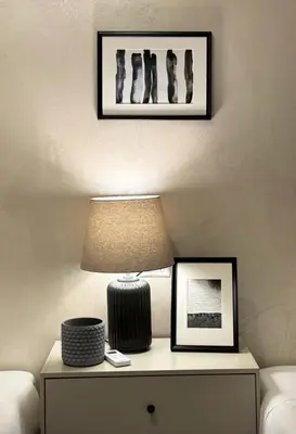 a table with a lamp and pictures on a wall at Ten Miles Guesthouse Roma in Rome