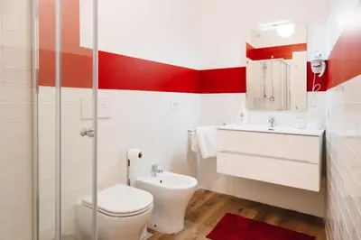 a red and white bathroom with a toilet and a sink at Famo Pace apartments in Rome