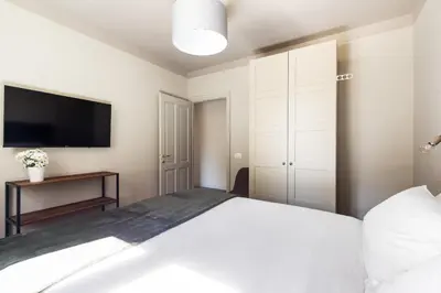 a bedroom with a white bed and a flat screen tv at Vatican Stunning 2 BR Apartment in Rome