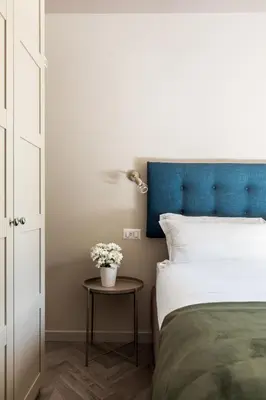 a bed with a blue headboard and a table with flowers at Vatican Stunning 2 BR Apartment in Rome