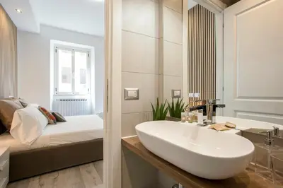 a bathroom with a white sink and a bed at Domus White in Rome