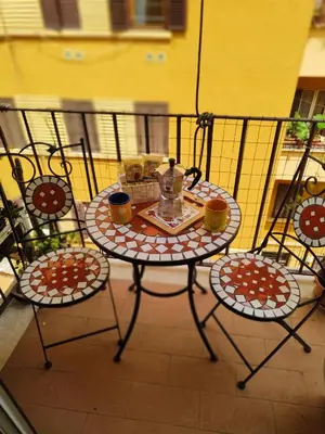 a table with two chairs and a tea set on a balcony at Il Nido di San Pietro - Cozy 2BR - Near Vatican in Rome