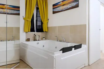 a white bath tub in a bathroom with yellow curtains at Dea Clodia studio flat in Rome