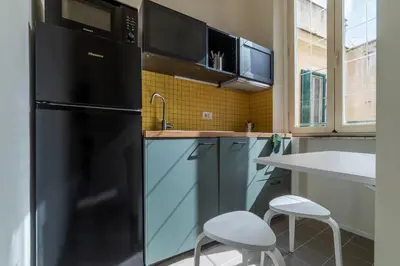 a kitchen with a black refrigerator and two stools at GuestHost - Colosseo & San Clemente Apartment in Rome