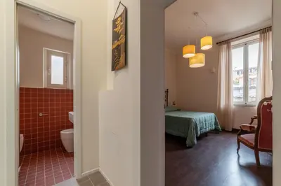 a bathroom with a toilet and a room with a bed at GuestHost - Colosseo & San Clemente Apartment in Rome