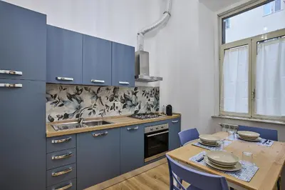 a kitchen with blue cabinets and a table with chairs at Casa Pallini Luxury Apartment in Rome