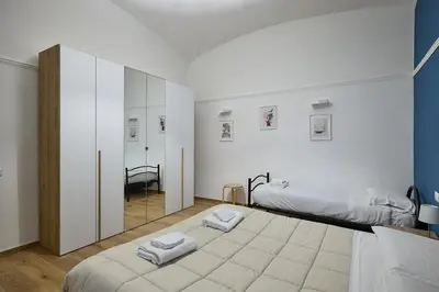 a white room with two beds and a mirror at Casa Pallini Luxury Apartment in Rome