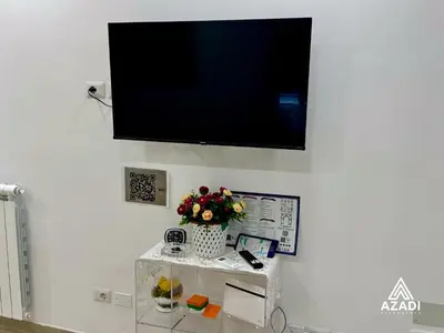 a flat screen tv on a wall with a vase of flowers at Azadi B&B Flaminio in Rome