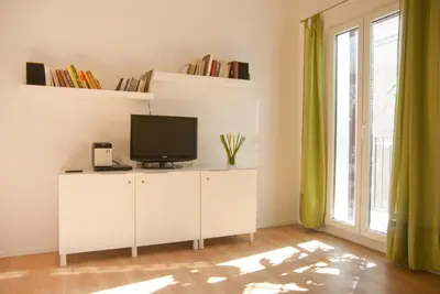 a tv on a white cabinet in a room with a window at Welcome Friends in Rome