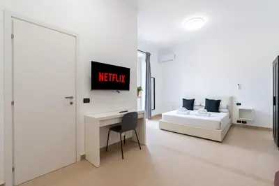 a white living room with a bed and a desk at San Giovanni Boutique Suites in Rome