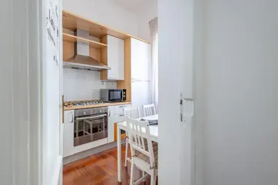a kitchen with white cabinets and a table with chairs at Your elegant Loft at Termini Station in Rome