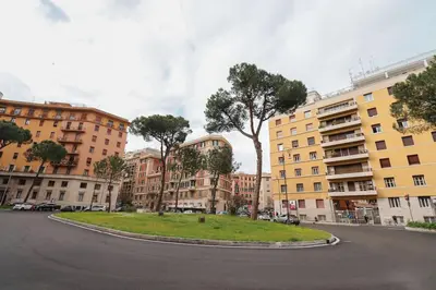 a street with buildings and a tree in the middle at cos24 in Rome