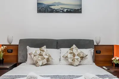 a bed with four pillows and a picture on the wall at STELLA GUEST HOUSE O AFFITTACAMERE in Rome