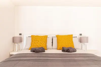 a white bed with yellow pillows and two towels on it at [Trastevere Lux* * * * *] - Roma Centro Storico in Rome