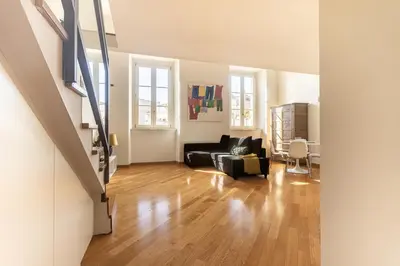 a living room with a black couch and wooden floors at [Trastevere Lux* * * * *] - Roma Centro Storico in Rome