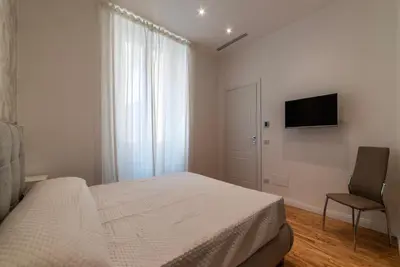 a bedroom with a bed and a chair and a television at GuestHost - Rome Huge & Cozy Apartment in Rome