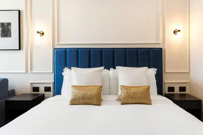 a bed with a blue headboard and two pillows at Adriana Boutique Guest House in Rome