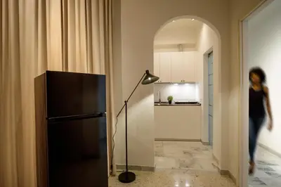 a woman walking through a hallway with a black refrigerator at The Right Place 4U Piemonte Apartment in Rome