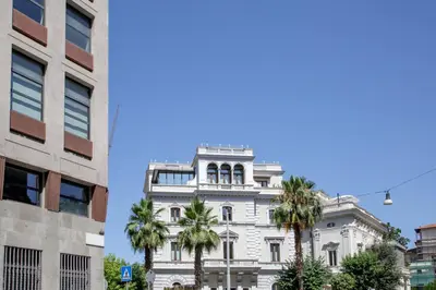 a white building with palm trees in front of it at The Right Place 4U Piemonte Apartment in Rome