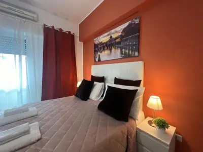 a bedroom with a large bed with an orange wall at affittacamere appia nuova 639 in Rome
