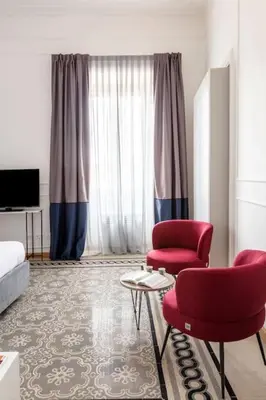 a living room with two red chairs and a bed at SJR Luxury Apartment Trevi Fountain in Rome
