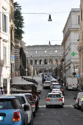 a busy city street with cars parked in front of a building at Colosseo studios in Rome