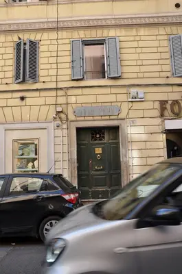 two cars parked in front of a building with a green door at Colosseo studios in Rome
