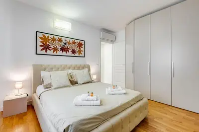 a white bedroom with a large bed with two towels at Valle Aurelia Vatican Home - Beutiful View & Wi-Fi in Rome