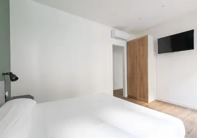 a white bedroom with a bed and a tv on the wall at Vatican family loft in Rome
