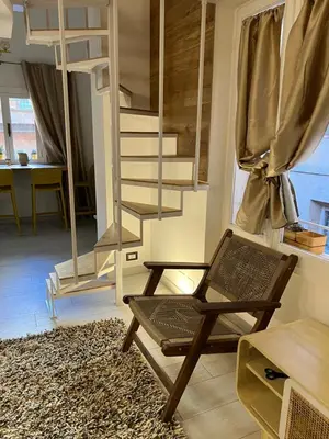 a living room with a chair and a spiral staircase at Loft a piazza di Spagna in Rome