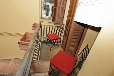 a balcony with two red chairs and a staircase at Bollo Studio in Rome
