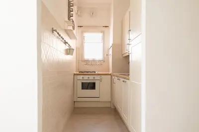 a small kitchen with white cabinets and a window at Roma per te in Rome