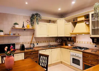 a kitchen with white cabinets and a wooden table at Vatican Terrace Apartment in Rome