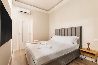 a white bedroom with a large bed with white pillows at Vatican Clodio Suites in Rome