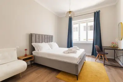 a white bedroom with a bed and a chair at Vatican Clodio Suites in Rome