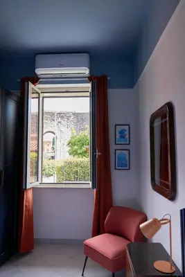a living room with a red chair and a window at Bivio - Casa Azzurra in Rome