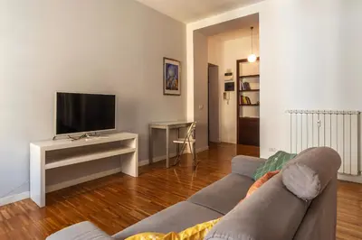 a living room with a couch and a tv at GuestHost - Chic Stay at Magnagrecia Rome Apartment in Rome