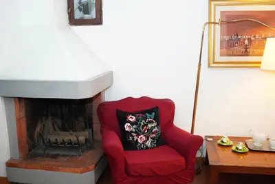 a red chair sitting in front of a fireplace at La Torre del Moro - RH Collection in Rome