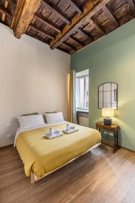 a bedroom with a large bed with a yellow bedspread at Sciampagne in Rome