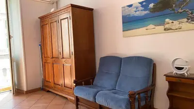 a room with a blue chair and a wooden cabinet at Colosseum home in Rome