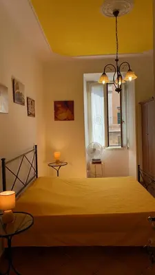 a bedroom with a yellow bed with two tables and a window at Colosseum home in Rome