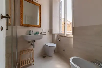 a bathroom with a sink and a toilet and a mirror at 2 BR Flat with Vatican Terrace in Rome
