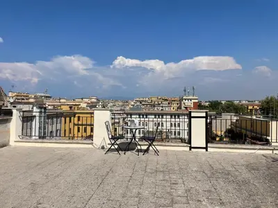 a patio with two chairs and a table on a roof at Val's Vatican Wall Apartment in Rome